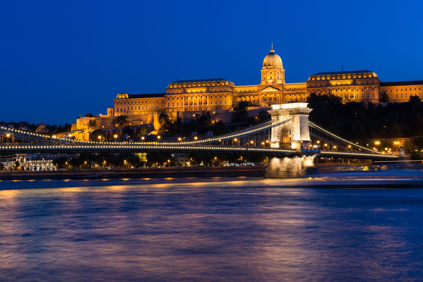 Budapest bridges: the Chain Bridge lit up at night with Buda Castle behind