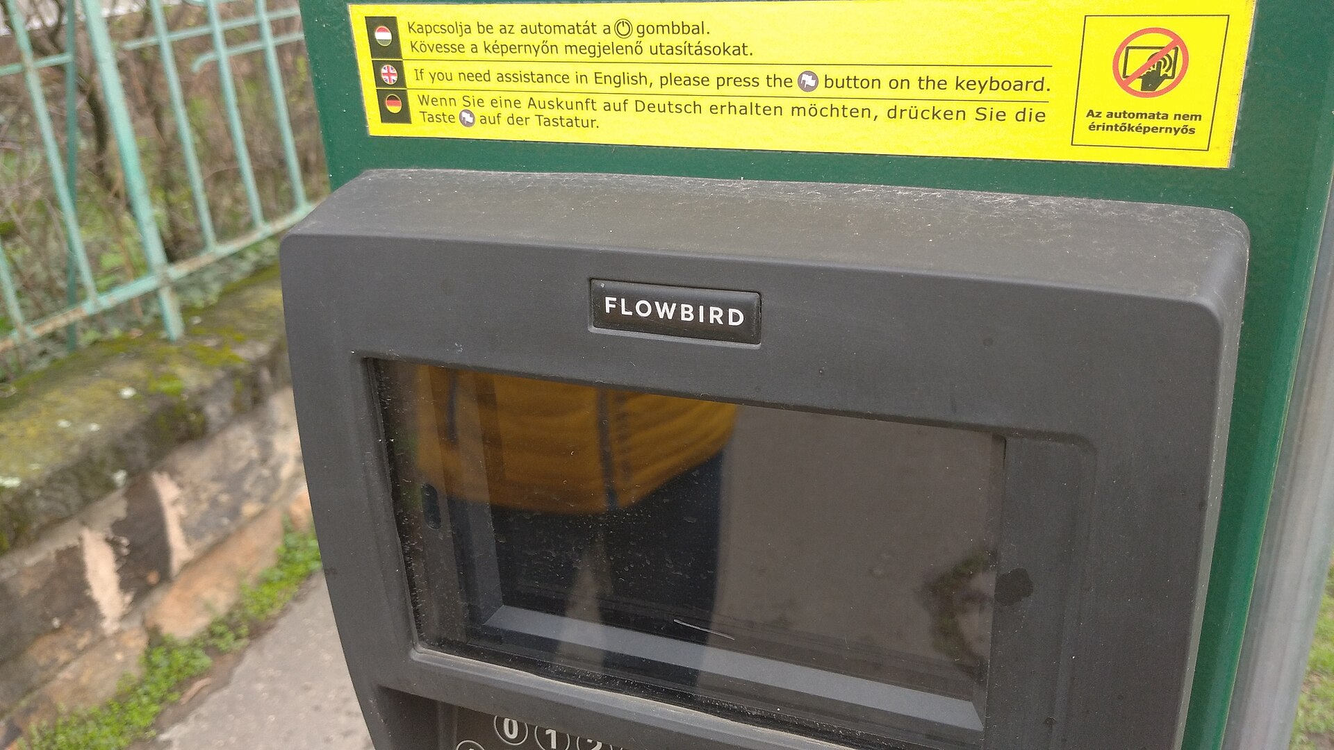 Close-up of a green Flowbird parking machine in Budapest, with instructions in Hungarian, English and German