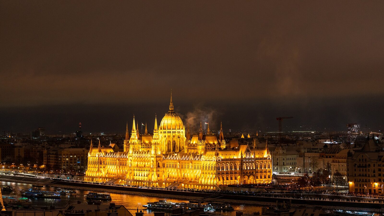 The Hungarian Parliament lit up at night across the Danube, seen over snow-covered rooftops in Buda