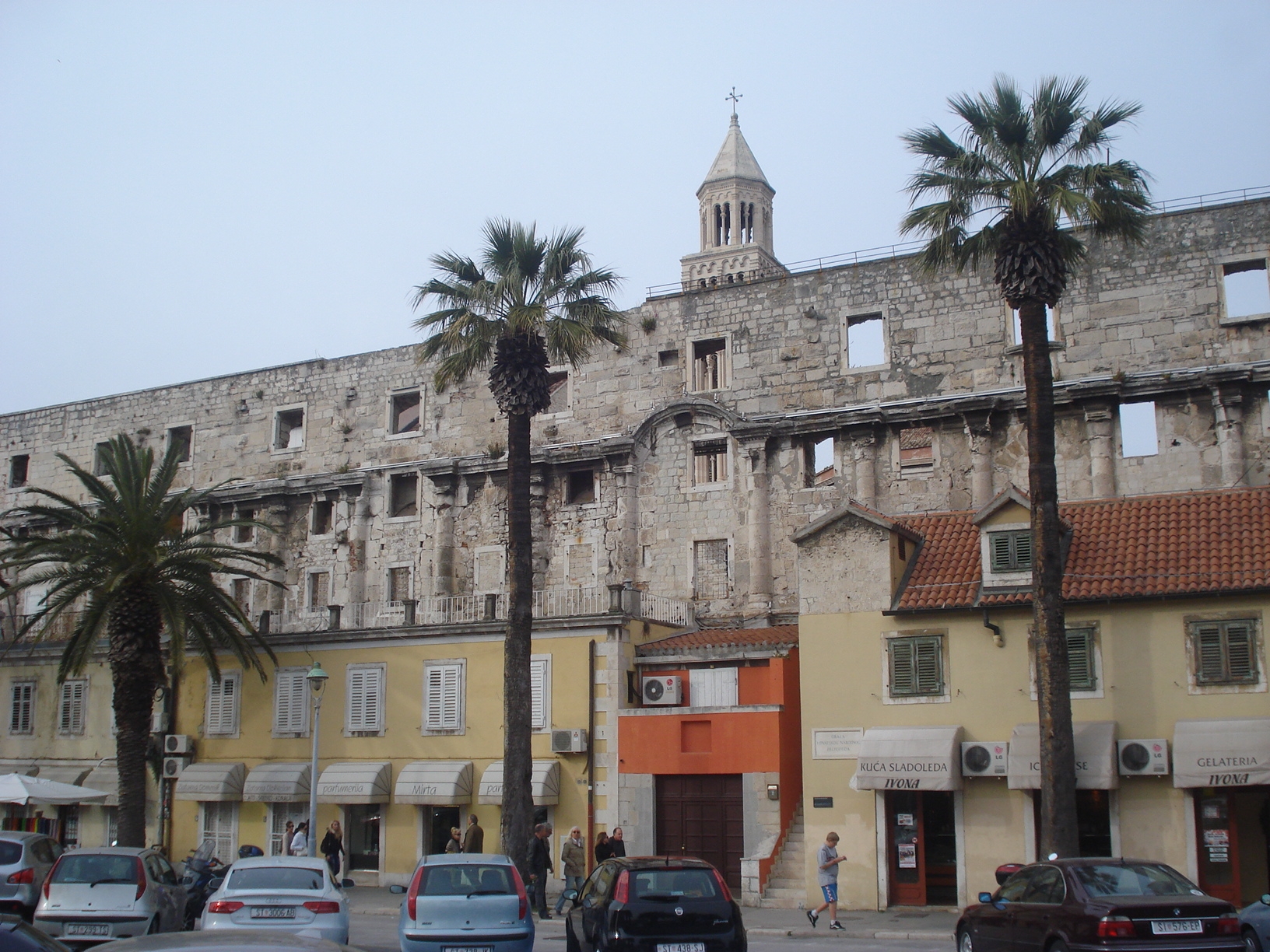 The south wall of Diocletian's Palace in Split, with the cathedral bell tower rising behind it and palm trees in front