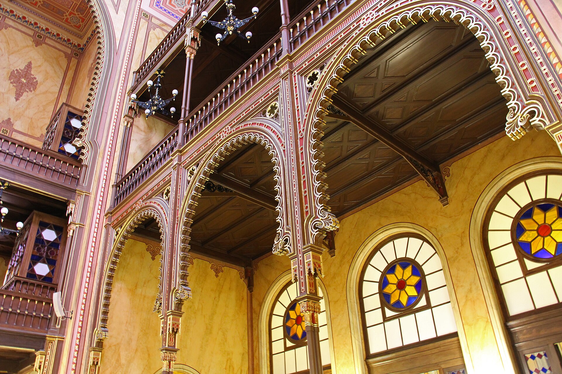 The interior of the Dohany Street Synagogue in Budapest showing tiered wooden galleries, painted arches and stained glass rosettes