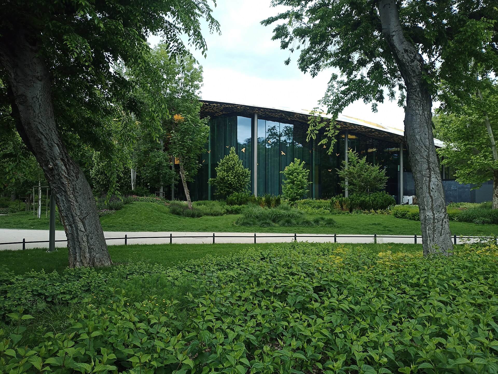 The House of Hungarian Music seen through the trees of Budapest's City Park, with its perforated curved roof