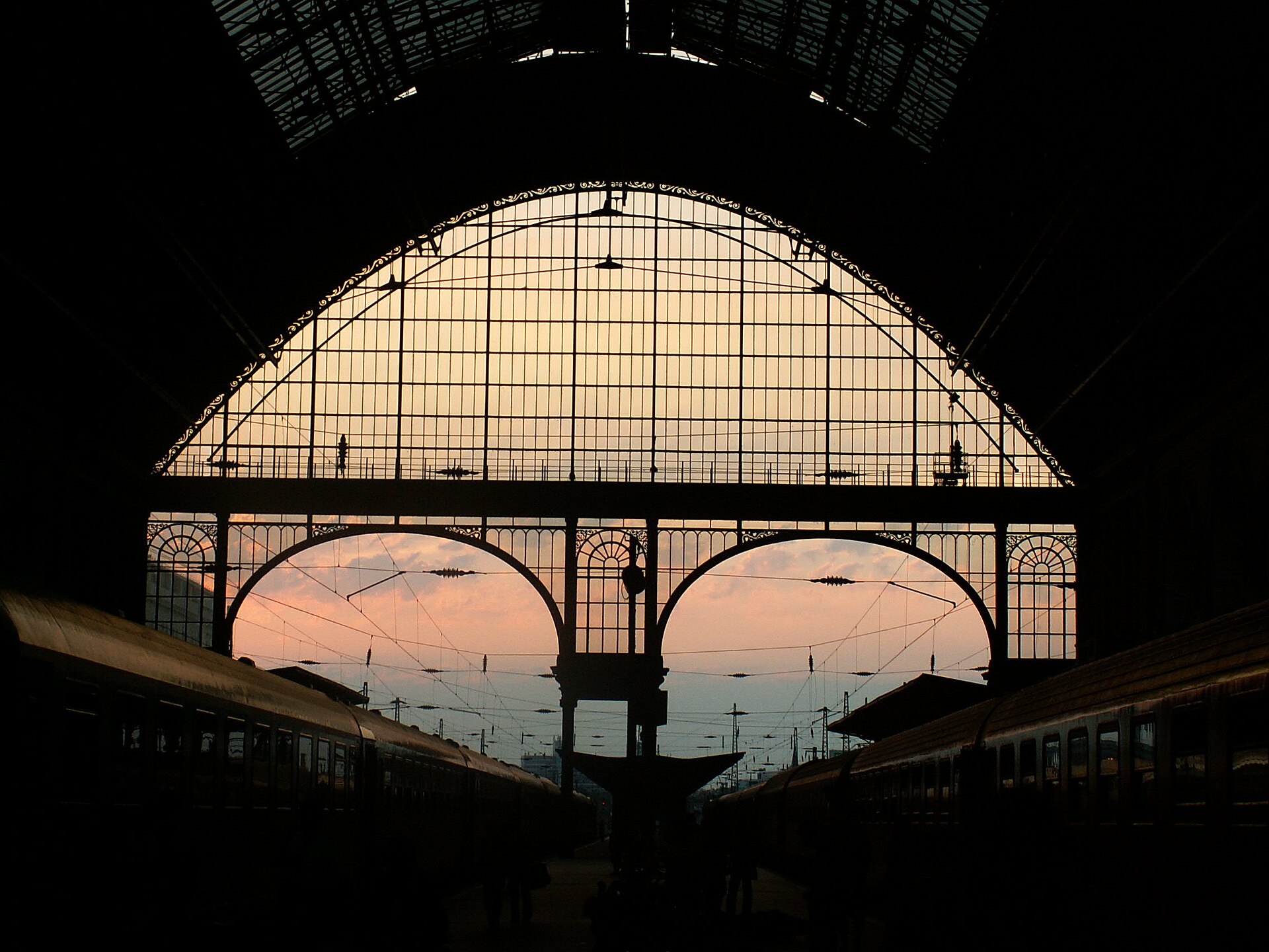The glass roof of Budapest's Keleti railway station silhouetted against a sunset sky