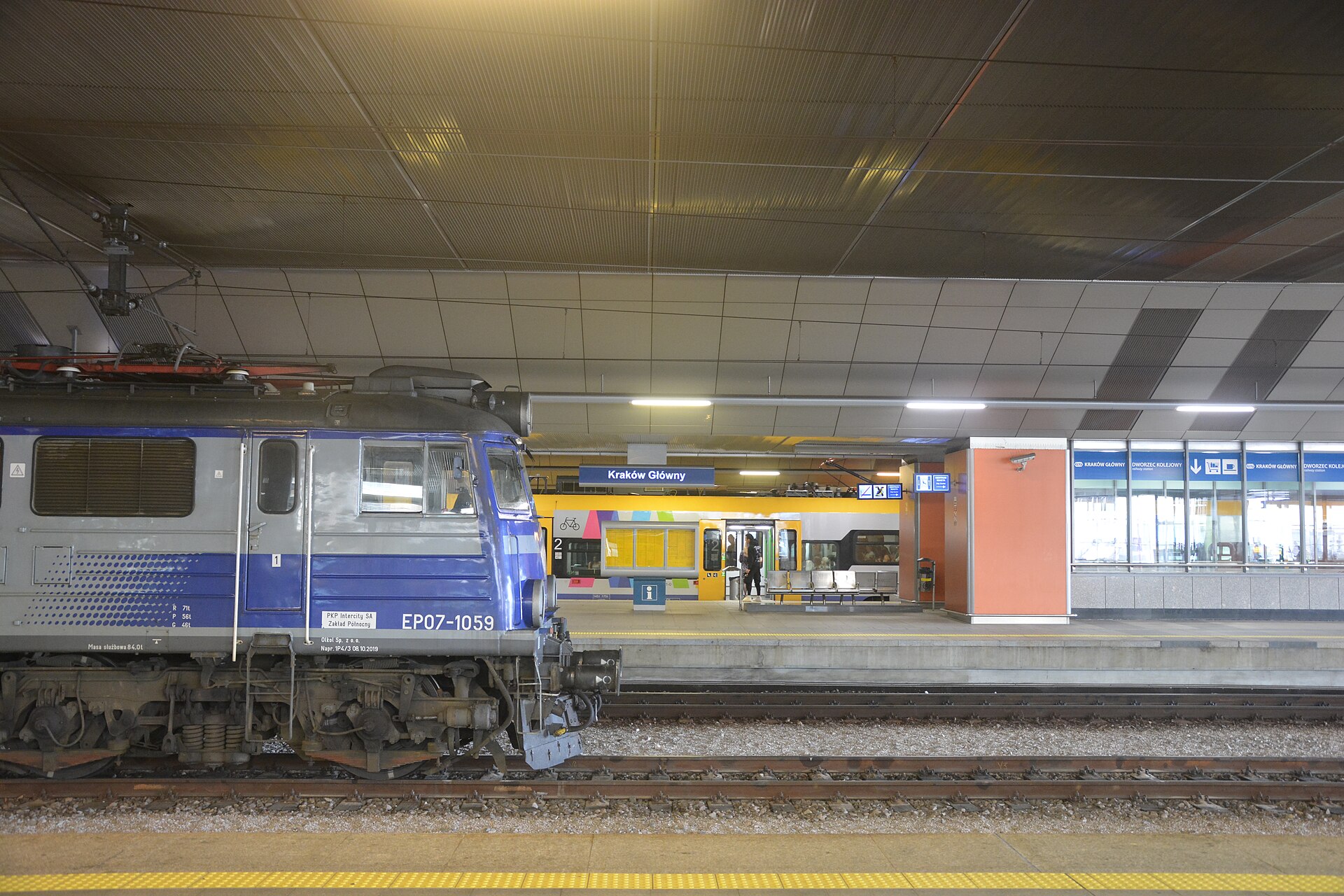 A PKP Intercity locomotive beside a platform at Kraków Główny station, with the station name sign above