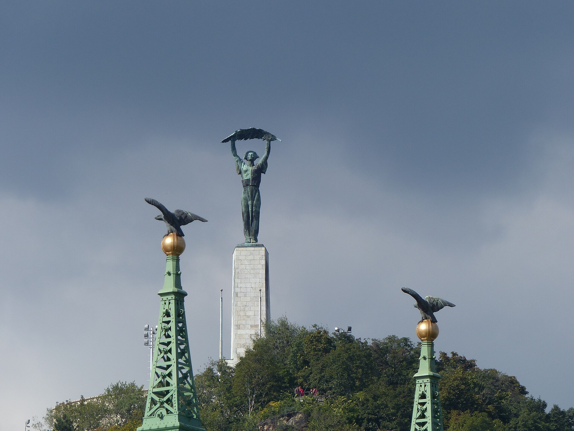 The Liberty Statue on top of Gellert Hill in Budapest, seen past the bronze turul eagles of Liberty Bridge