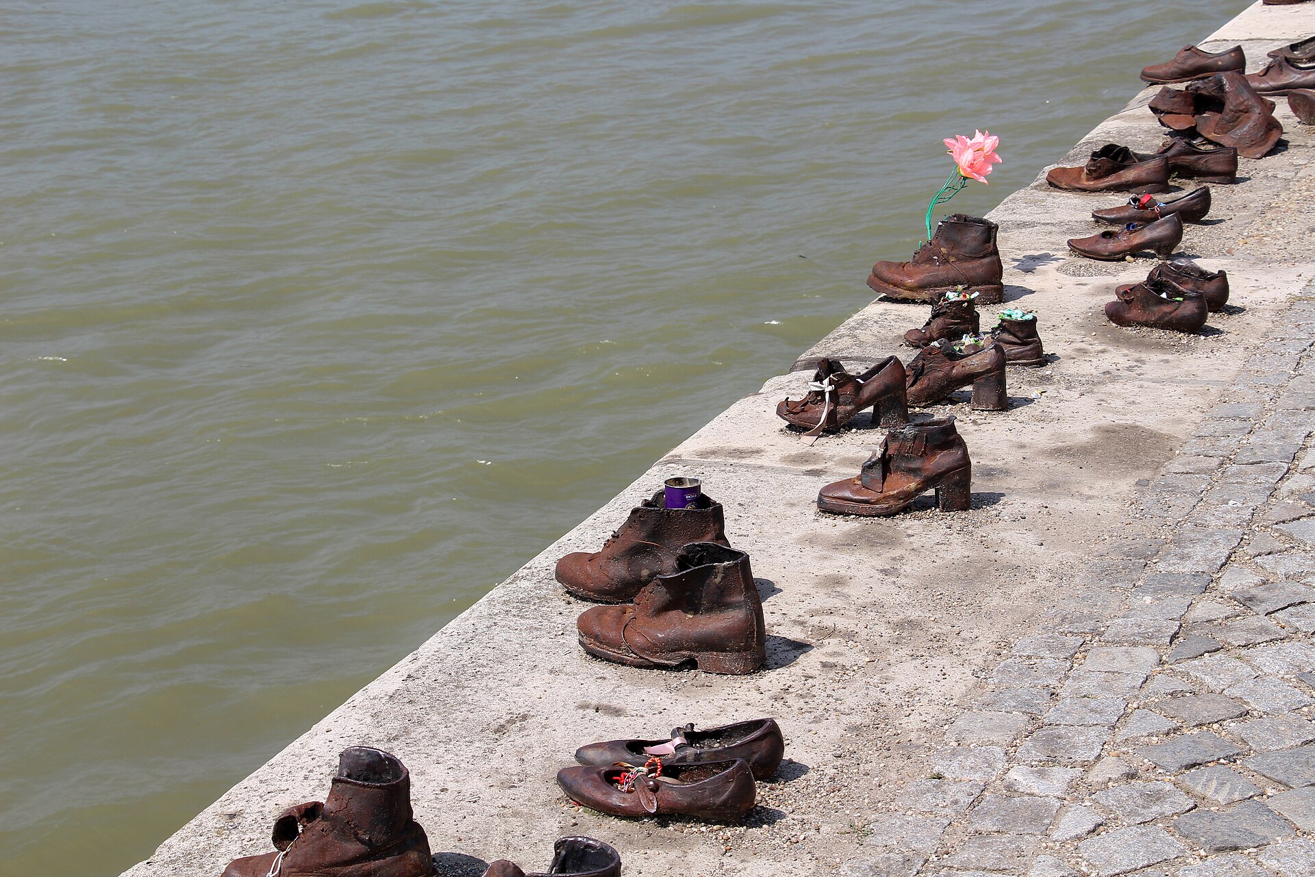 Close view of individual iron shoes on the Danube embankment, with a candle and a flower left inside them