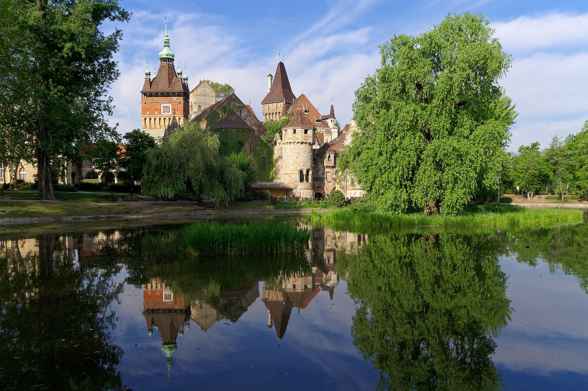 Vajdahunyad Castle in Budapest reflected in the lake in front of it, with willow trees framing the view